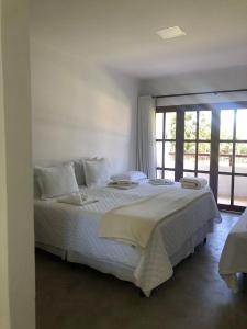 a bedroom with a large white bed with a window at Pousada Calugi in Triunfo