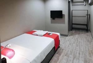 a small room with a bed and a flat screen tv at Central District Hotel Davao in Davao City