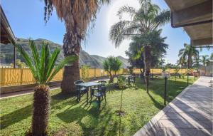 un patio con tavoli, palme e montagne di Awesome Home In Melito Di Porto Salvo With Wifi a Melito di Porto Salvo