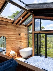 Habitación con ventanas y baño con bañera. en lacascatachales Chale Aspen, en Urubici