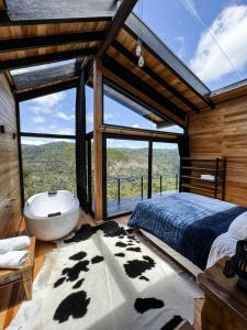 1 dormitorio con bañera y ventana grande en lacascatachales Chale Aspen, en Urubici