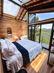 1 dormitorio con 1 cama en una habitación con ventanas en lacascatachales Chale Aspen, en Urubici