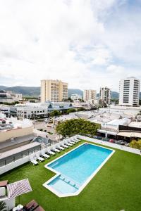 an overhead view of a large swimming pool with lawn chairs and buildings at The Benson Hotel in Cairns