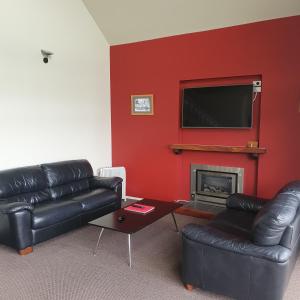 a living room with two leather couches and a fireplace at Kiwi on the Lake 3 bedroom,Chalet Villa in Rotorua