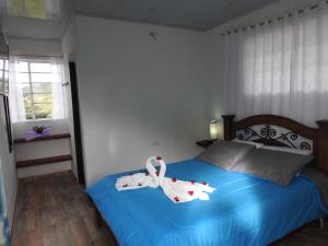 een slaapkamer met een blauw bed en handdoeken bij Posada Rural Villa Rouse in Guachantivá