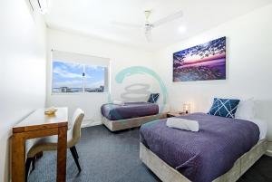 a bedroom with two beds and a desk and a table at ZEN BY THE WATER - Darwin's Premier Ocean View Family Retreat in Darwin