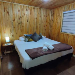 a bedroom with a bed in a wooden cabin at Cabañas Puerto Aysen in Puerto Aisén