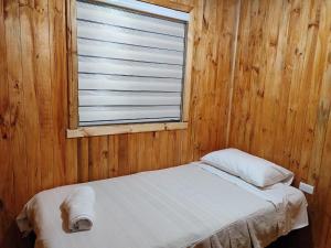 a bed in a wooden room with a window at Cabañas Puerto Aysen in Puerto Aisén