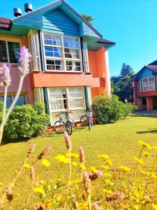 una casa con un jardín con flores delante en Belíssimo Duplex a 500m Lago Neg 3Q 4bikes Churrasq lareira Ar QF, en Gramado