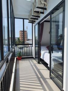 a balcony with a bed and windows on a building at Paradise Cozy Guesthouse Sihanoukville in Sihanoukville
