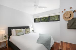 1 dormitorio con 1 cama blanca y ventana en Timboon Tiny Homes, en Timboon