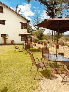 un patio con mesa, sillas y sombrilla en Lo Nuestro - Hospedaje, en Villa de Leyva