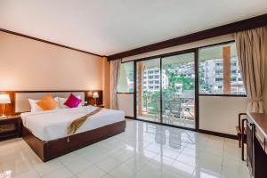 a bedroom with a bed and a large window at Bauman Ville Hotel in Patong Beach