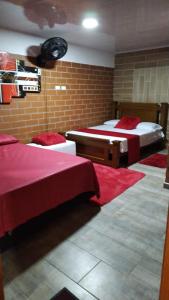 a bedroom with two beds with red sheets at El Buen Sazon Valluno 