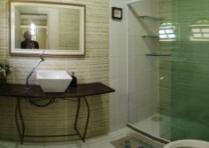 uma casa de banho com um lavatório, um espelho e um chuveiro em Pousada nascente do sol em Macaé