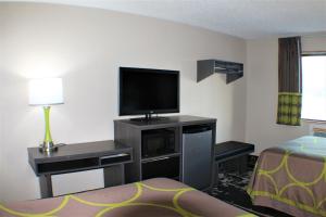 a hotel room with a flat screen tv and a bed at Super 8 by Wyndham Greensboro/Coliseum/Conv. in Greensboro