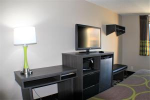 a hotel room with a television and a desk with a lamp at Super 8 by Wyndham Greensboro/Coliseum/Conv. in Greensboro +7 photos