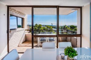 a room with a table and chairs and a large window at Retro Style Apartment Kings Beach with Ocean Views in Caloundra