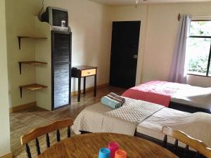 a room with two beds and a table and a tv at Villas el Cenizaro in La Garita