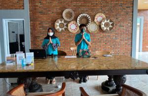 two people wearing face masks standing at a table at Alinson Sunset Hill in Bogor