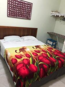 uma cama com um cobertor vermelho e amarelo em Flat 102 em Riviera de São Lourenço