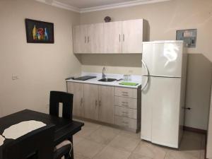 a kitchen with a white refrigerator and a table at SUITE DORAL ¡¡CERCA DEL AEROPUERTO!! in Guayaquil
