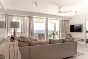 Una sala de estar con un sofá y una ventana grande. en Noosa Crest Penthouse 37 - Private Rooftop Pool, en Noosa Heads