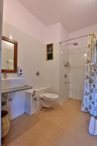 a white bathroom with a toilet and a sink at Bison Retreat - Pench 