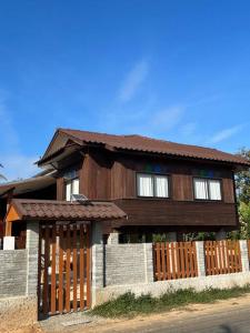 una casa in legno con una recinzione di fronte ad essa di BUA Homestay : cozy house in Laplae district a Uttaradit