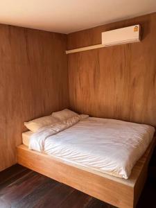 a bed in a room with a wooden wall at BUA Homestay : cozy house in Laplae district in Uttaradit