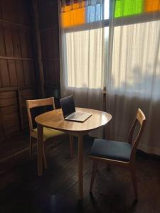 a laptop computer sitting on a table with two chairs at BUA Homestay : cozy house in Laplae district in Uttaradit