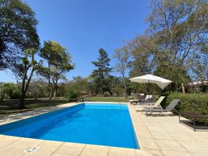 a swimming pool with an umbrella and two chairs and a table at Finca La Secundina in Salta
