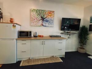 a kitchen with a desk with a microwave and a tv at Ramada Resort - Stylish Deluxe Apartment in Port Douglas