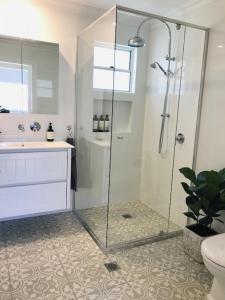 a bathroom with a shower and a sink and a toilet at Seabirds Cottage in Coffs Harbour