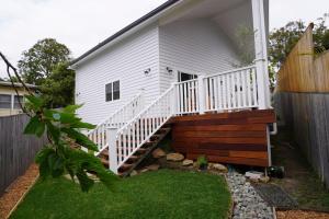 a white house with a staircase leading to a yard at Seabirds Cottage in Coffs Harbour