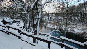 a fence covered in snow next to a river at Namelis Šiaurėje in Kaltanėnai