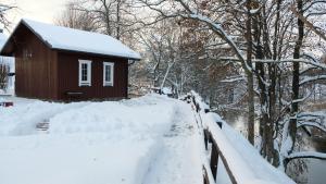 een huis bedekt met sneeuw naast een hek bij Namelis Šiaurėje in Kaltanėnai