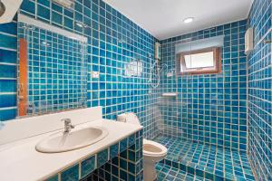 W wyłożonej niebieskimi kafelkami łazience znajduje się umywalka i toaleta. w obiekcie Chill Inn Lipa Noi Hostel and Beach Cafe w mieście Koh Samui