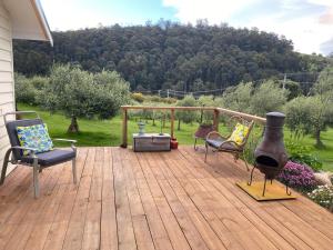 a wooden deck with two chairs and a grill at Wanderers Cottage in Woodbridge