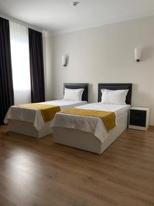 two beds in a hotel room with two bedsskirts at Deluxe Ferghana Hotel in Fergana