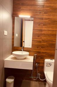 een badkamer met een wastafel, een toilet en een spiegel bij The Lavender Resort Waynad in Vaduvanchal