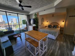 Un dormitorio con una cama, una mesa y un sofá. en Stylish Studio Apartment, Holiday Resort, With View, Pool, Spa , Sauna, en Gold Coast