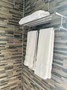 La salle de bains est pourvue de serviettes blanches sur un porte-serviettes. dans l'établissement Suite by the Pool, à Fa'a'ā
