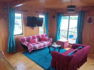 ein Wohnzimmer mit einem rosa Sofa und 2 Stühlen in der Unterkunft CABAÑAS RAYEN HUILLINCO in Chonchi