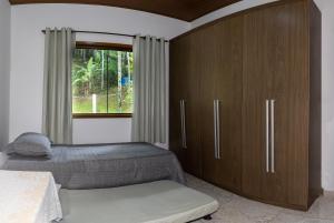 1 dormitorio con 1 cama y un gran armario de madera en Linda Casa em Buenos Aires Guarapari, en Guarapari