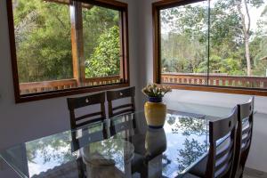 comedor con mesa de cristal y ventanas en Linda Casa em Buenos Aires Guarapari, en Guarapari