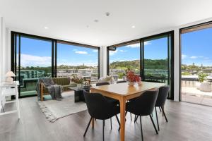a dining room with a table and chairs and windows at Enfield Sky - Brand New Luxury Penthouse in Auckland