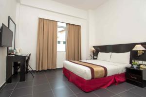 una camera d'albergo con letto, scrivania e TV di Swan Garden Hotel a Pasir Gudang