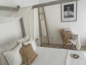 een witte slaapkamer met een bed en een stoel bij Fig&Olive Luxury one bedroom boutique in Pachna in Limassol