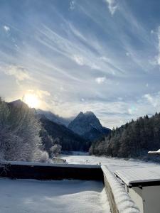 - une vue sur la rivière enneigée et les montagnes dans l'établissement Ferienwohnungen - Seehaus Riessersee, à Garmisch-Partenkirchen